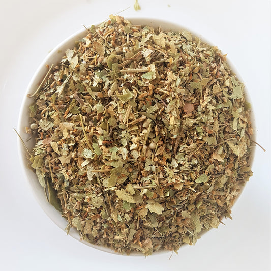 Dried Linden flower tea in a bowl against a white background. Top down view provided. Looks like a mixture of linden flowers and leaves and bits of back of the linden tree. Colours are light green and brown. Medicinal herbal tea mix which is said to assist against stress, anxiety, inflammation, pain, and high blood pressure. Diuretic effect also.