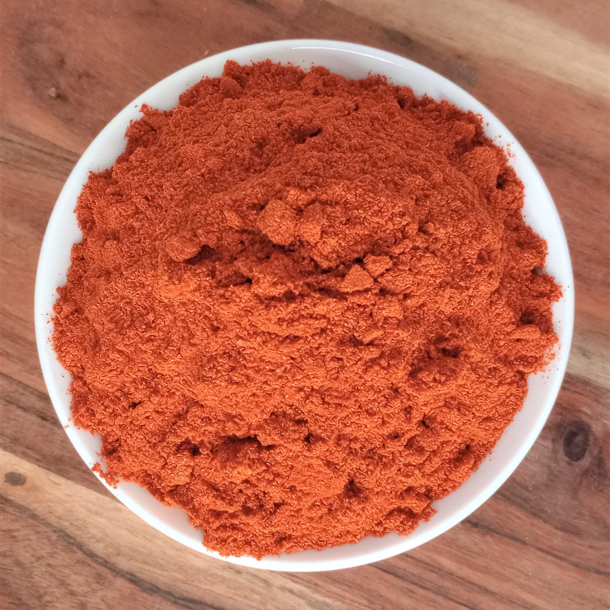 organic cayenne powder in bowl on wooden board