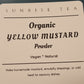 Label for Organic Yellow Mustard Powder by Sunrise Tea on a dark surface