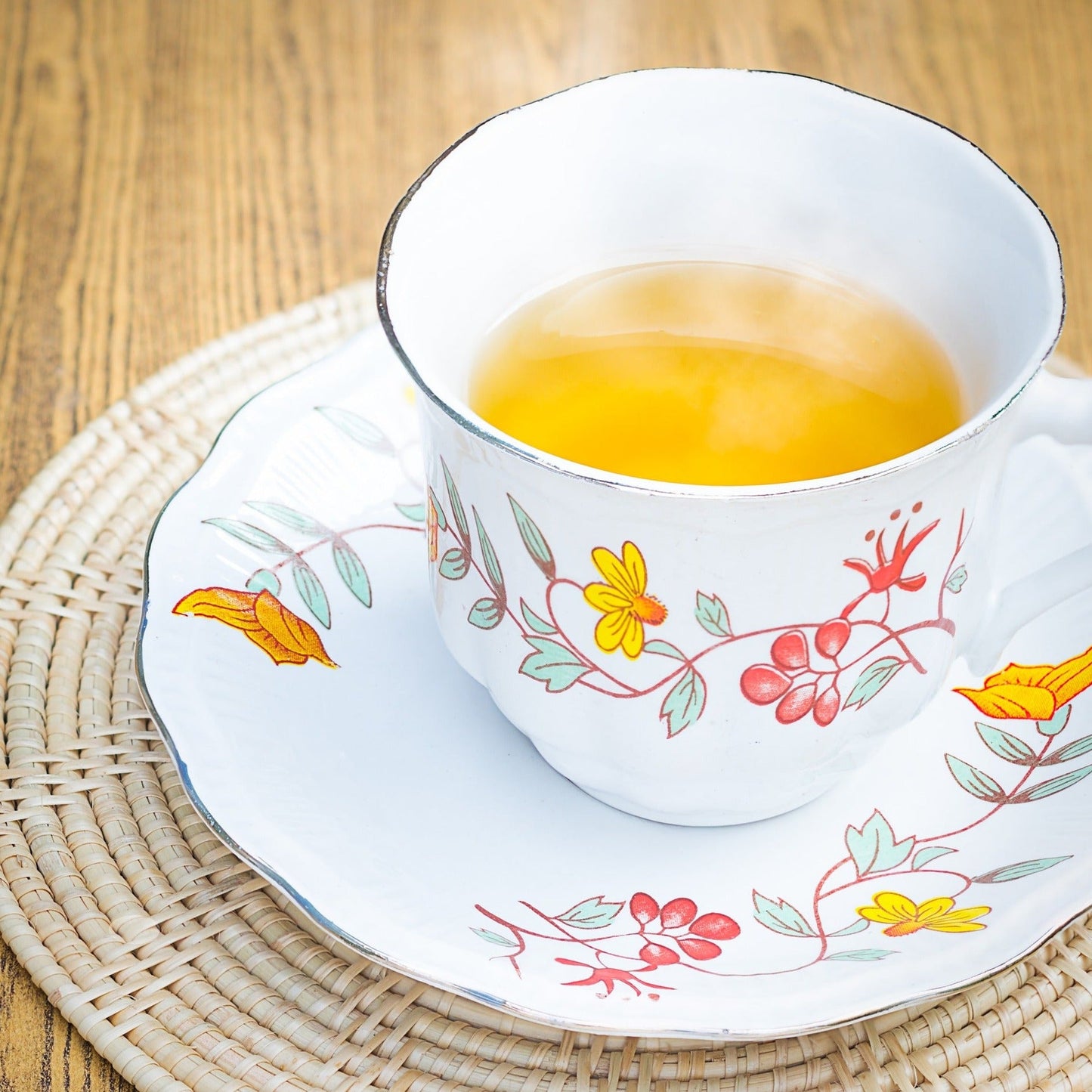 A pretty picture of epilobium tea served in a  traditional flower design tea cup and saucer. Tea is a an attractive honey colour.