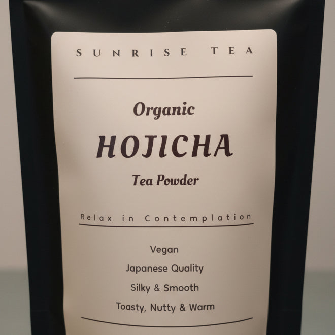 A close-up of a white pouch of Sunrise Tea Organic Hojicha Tea Powder, showing the text 'Hojicha', 'Organic', and 'Tea Powder' in black lettering.