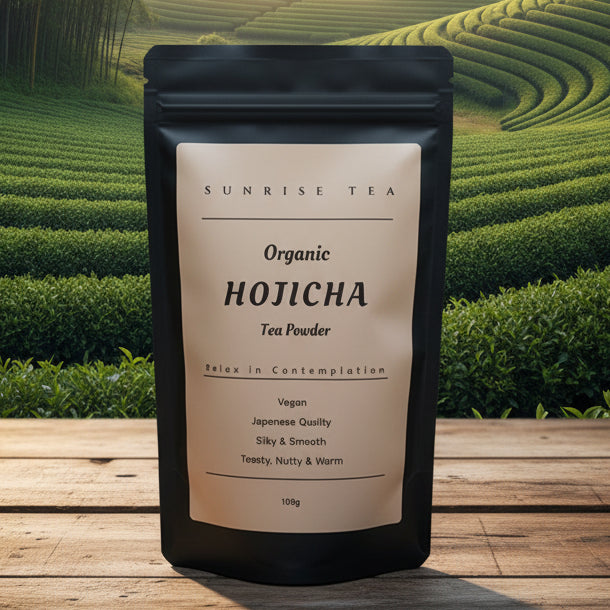 A 100g stand-up pouch of Sunrise Tea Organic Hojicha Tea Powder, set against a scenic background of green tea plantation hills and a wooden deck.