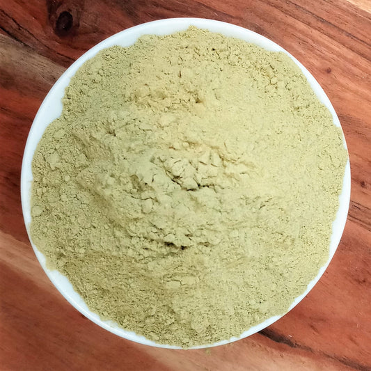 organic broccoli powder in a bowl on a wooden board