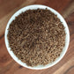 organic caraway seeds in a white bowl on a wooden board