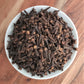 organic cloves in bowl on wooden board