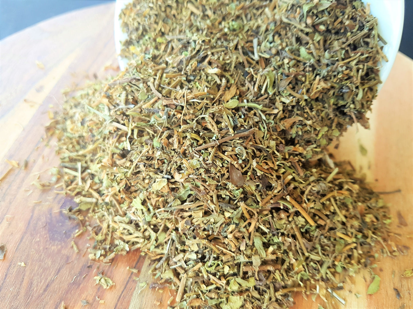 organic brahmi herb spilling out of bowl on to a wooden board