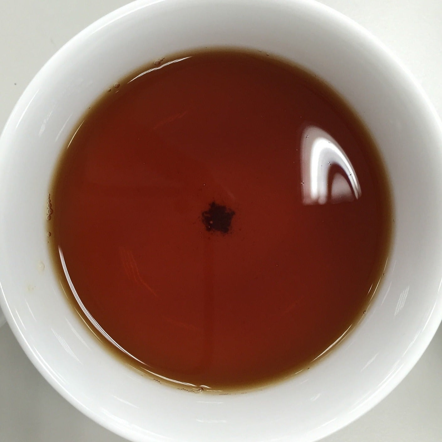 Oolong tea when steeped for a while produces a brown malty coloured beverage. This photo shows what an oolong brew could look like in a pretty white tea cup from a top down view.