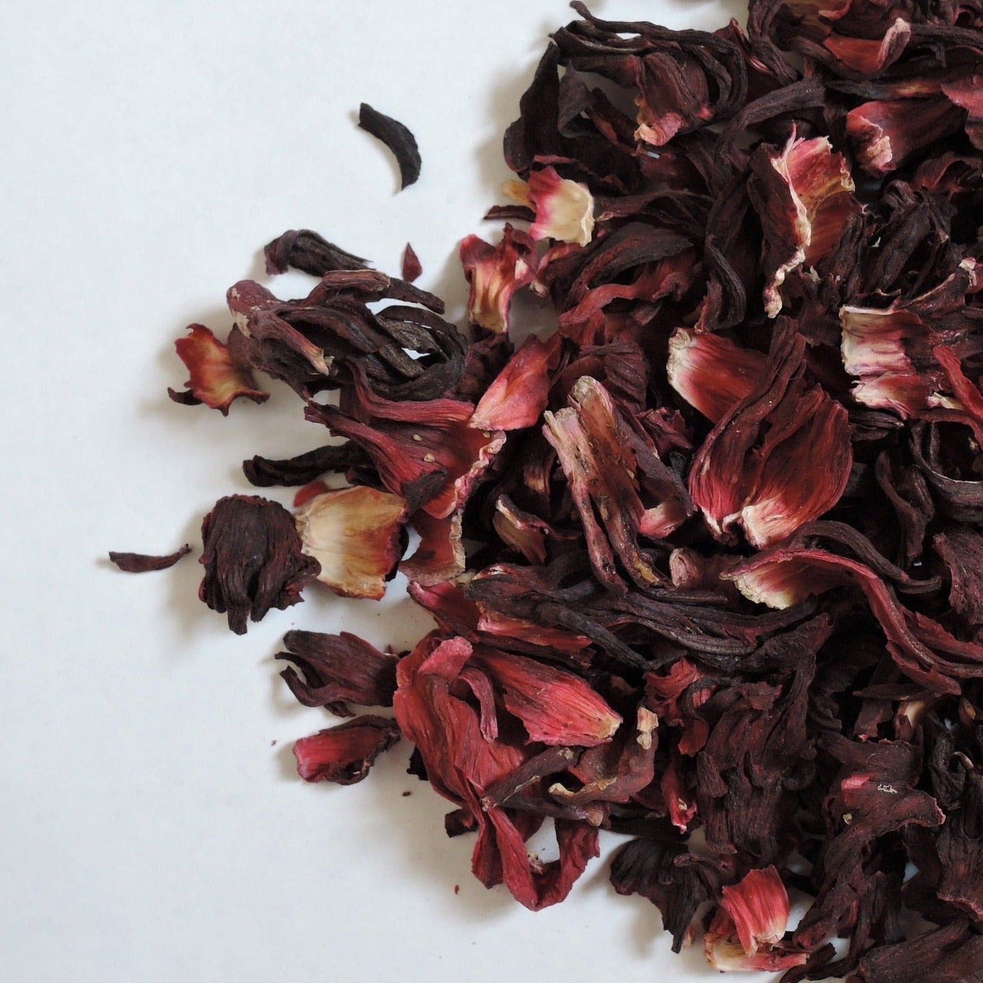 Beautiful pile of dried hibiscus flowers used for making tea. Artistically stylised to fill up only three quarters of the image. Background is white. Hibiscus tea isBeautiful pile of dried red hibiscus flowers used for making tea. Artistically stylised to fill up only three quarters of the image. Background is white. Full of antioxidants. Helps with weight loss, liver issues, blood fats, etc.