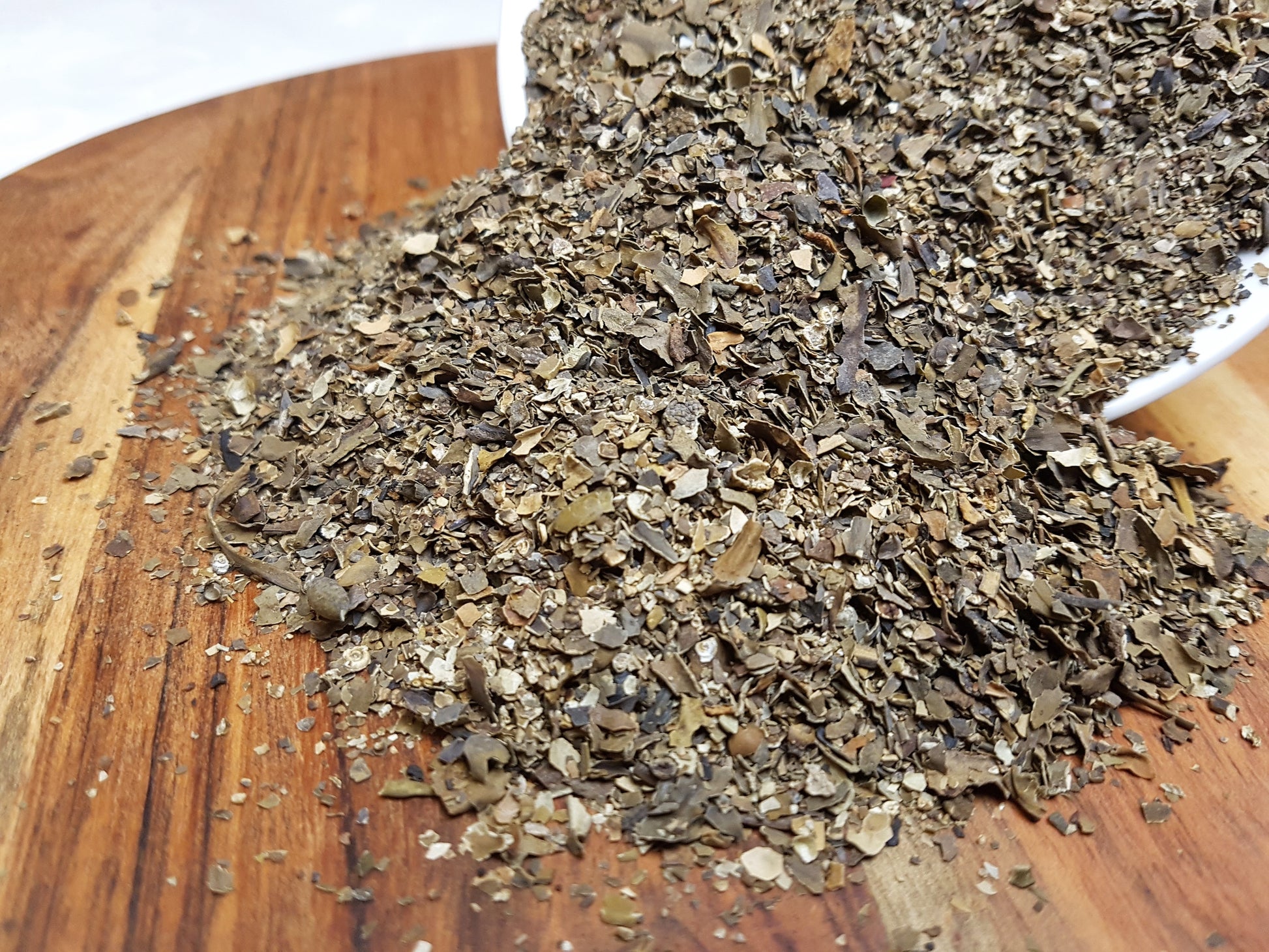 organic bladderwrack granules pouring out of a bowl on to a board